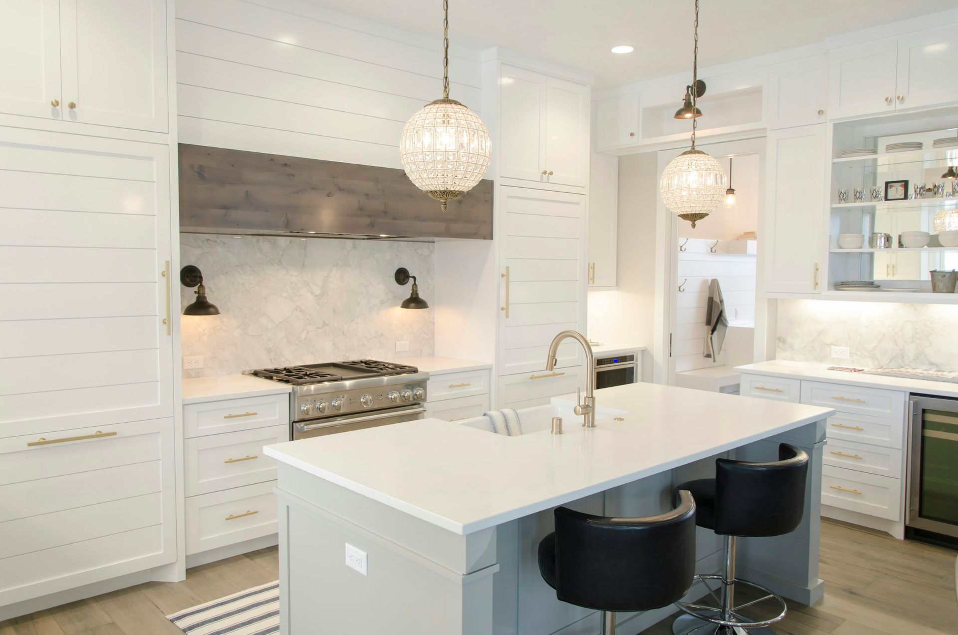 Modern white kitchen with island, countertops, and two hanging globe lights.