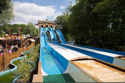 Water slide at an amusement park. People in boats slide down the blue water slides, splashing.