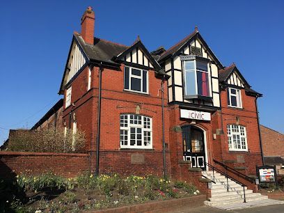 Red brick building with white trim, black accents, and a sign that reads 