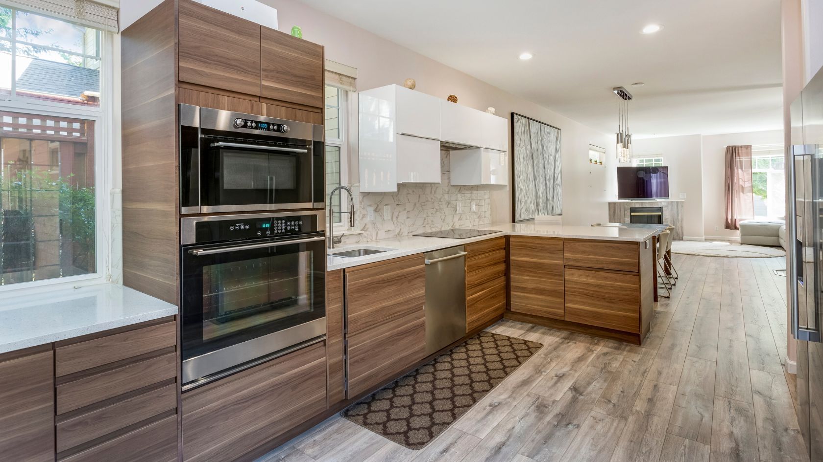 Modern kitchen with wood cabinets, white countertops, stainless steel appliances, and a center island.