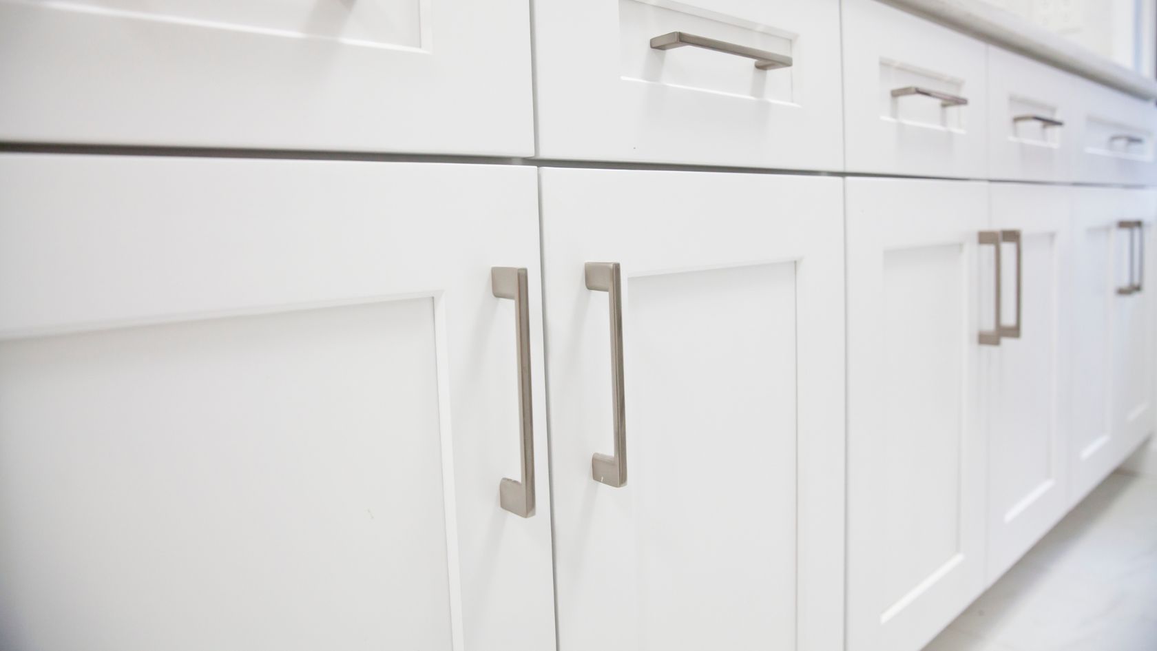 White kitchen cabinets with silver handles.