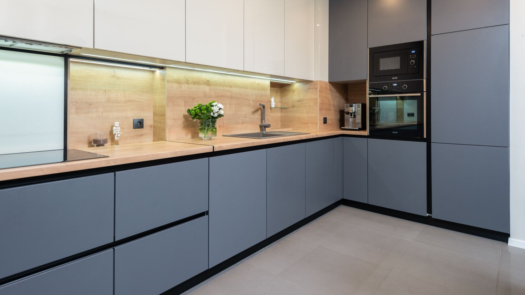 Modern kitchen with gray and white cabinets, wood countertops, and built-in appliances.