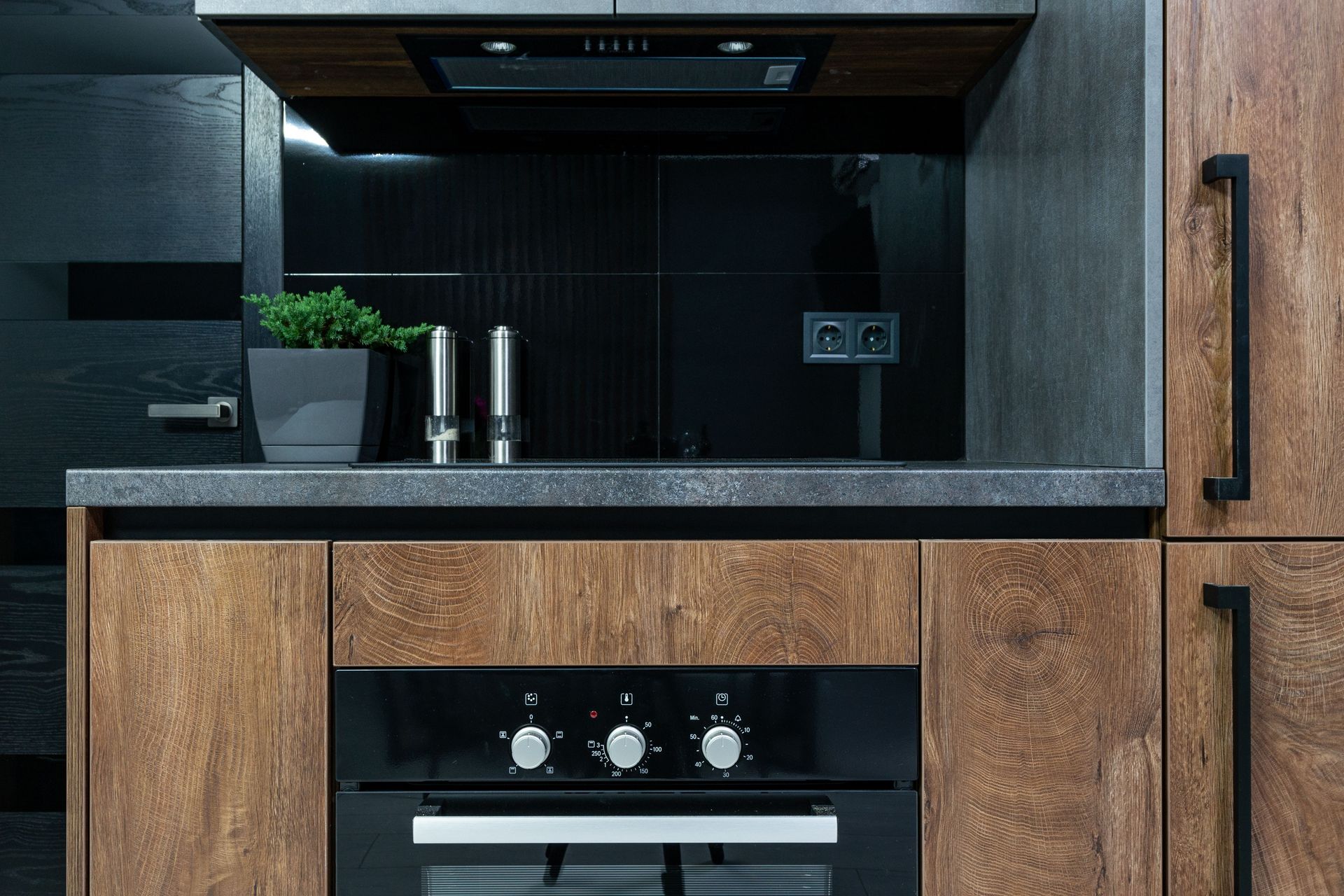 Modern kitchen with black backsplash, wood cabinets, sink, and built-in oven