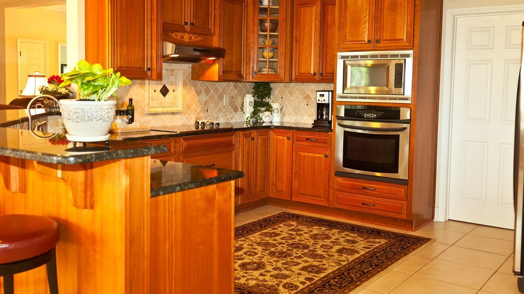 Kitchen with wood cabinets, granite countertops, and a patterned rug.