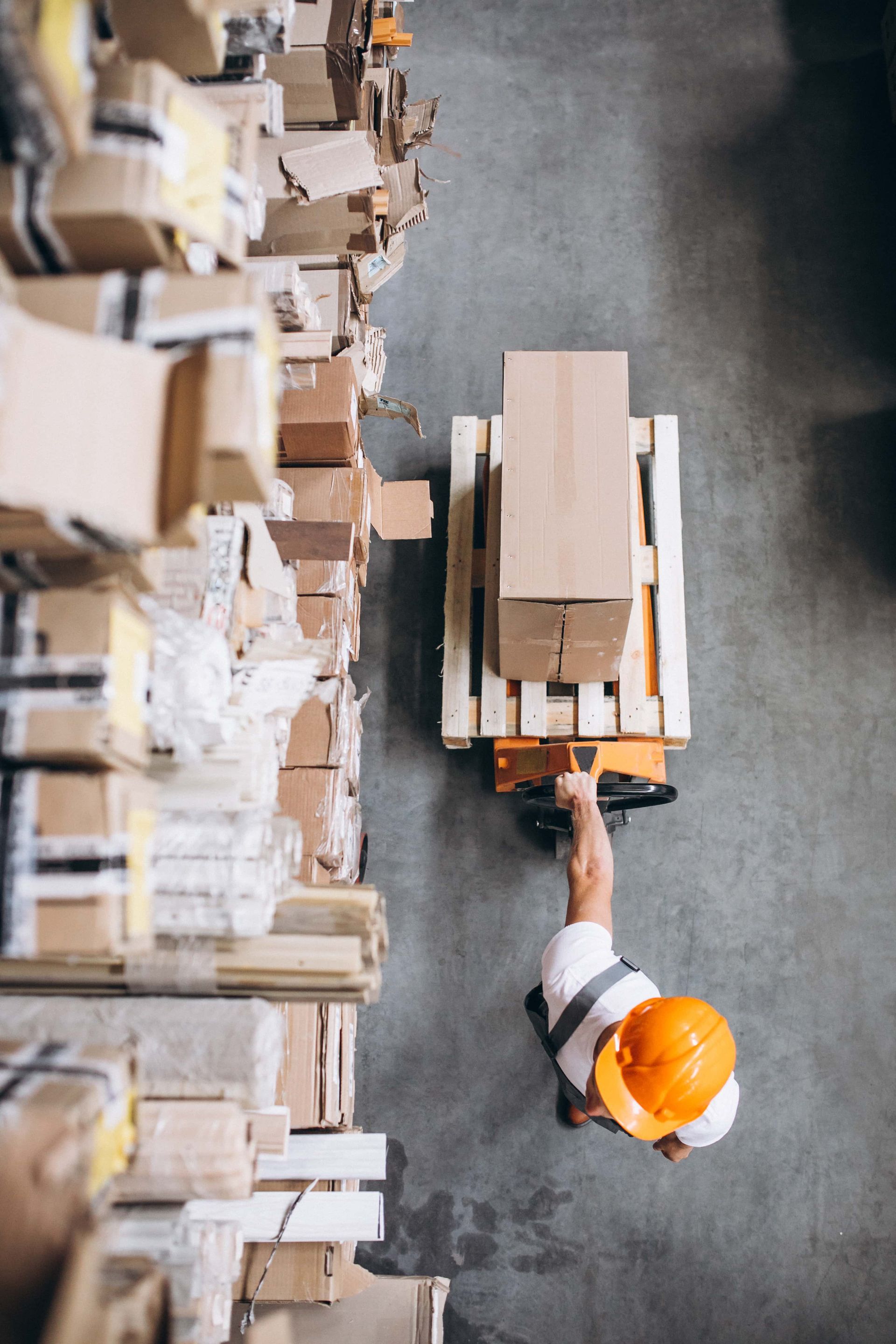 A Man Is Pushing a Pallet Truck With a Box on It in a Warehouse