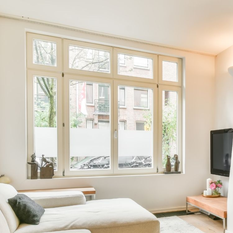 Bright living room with large windows, sofa, and television.