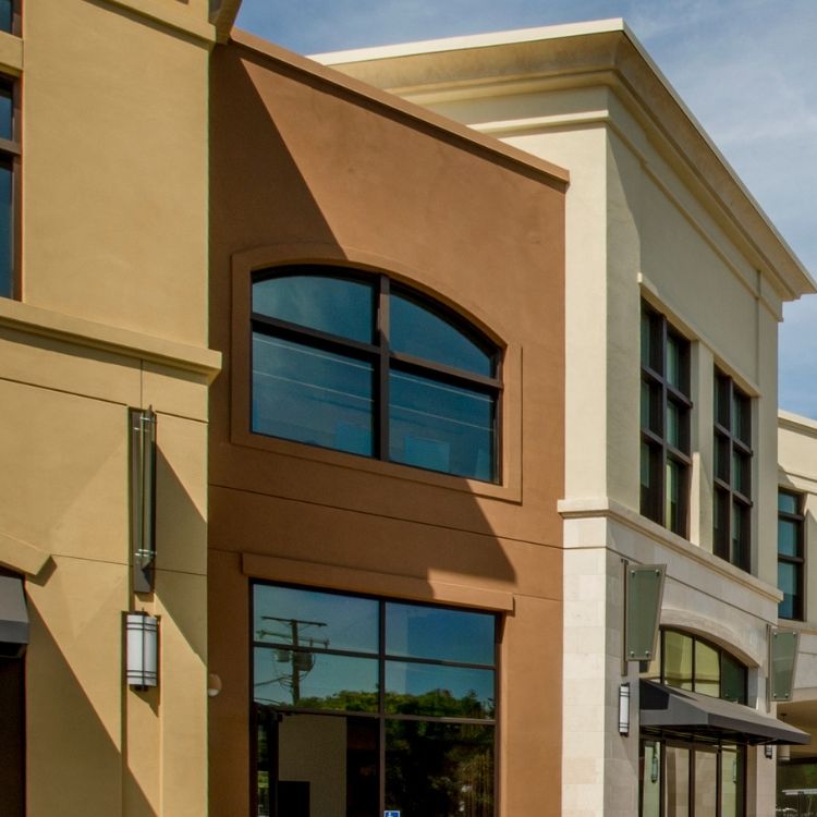Buildings with different colored facades, brown and tan, featuring arched and rectangular windows.