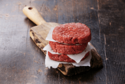 hamburger patties on wooden paddle
