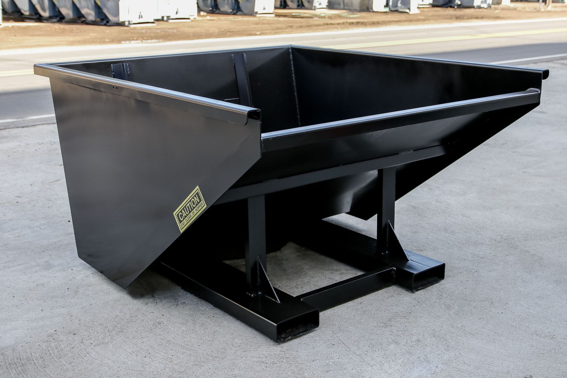 A large black dumpster is sitting on the side of the road