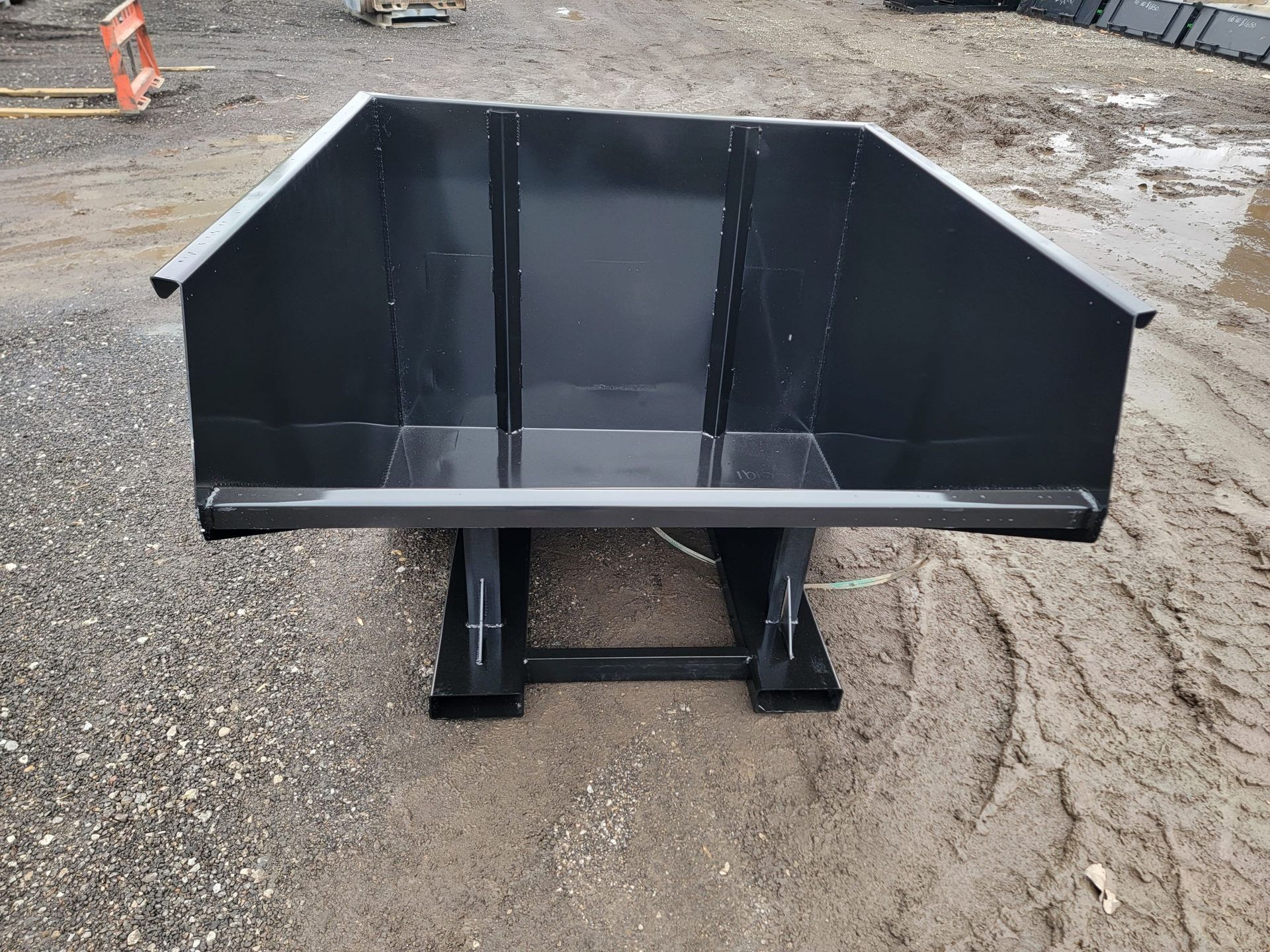 A large black dumpster is sitting on the side of the road