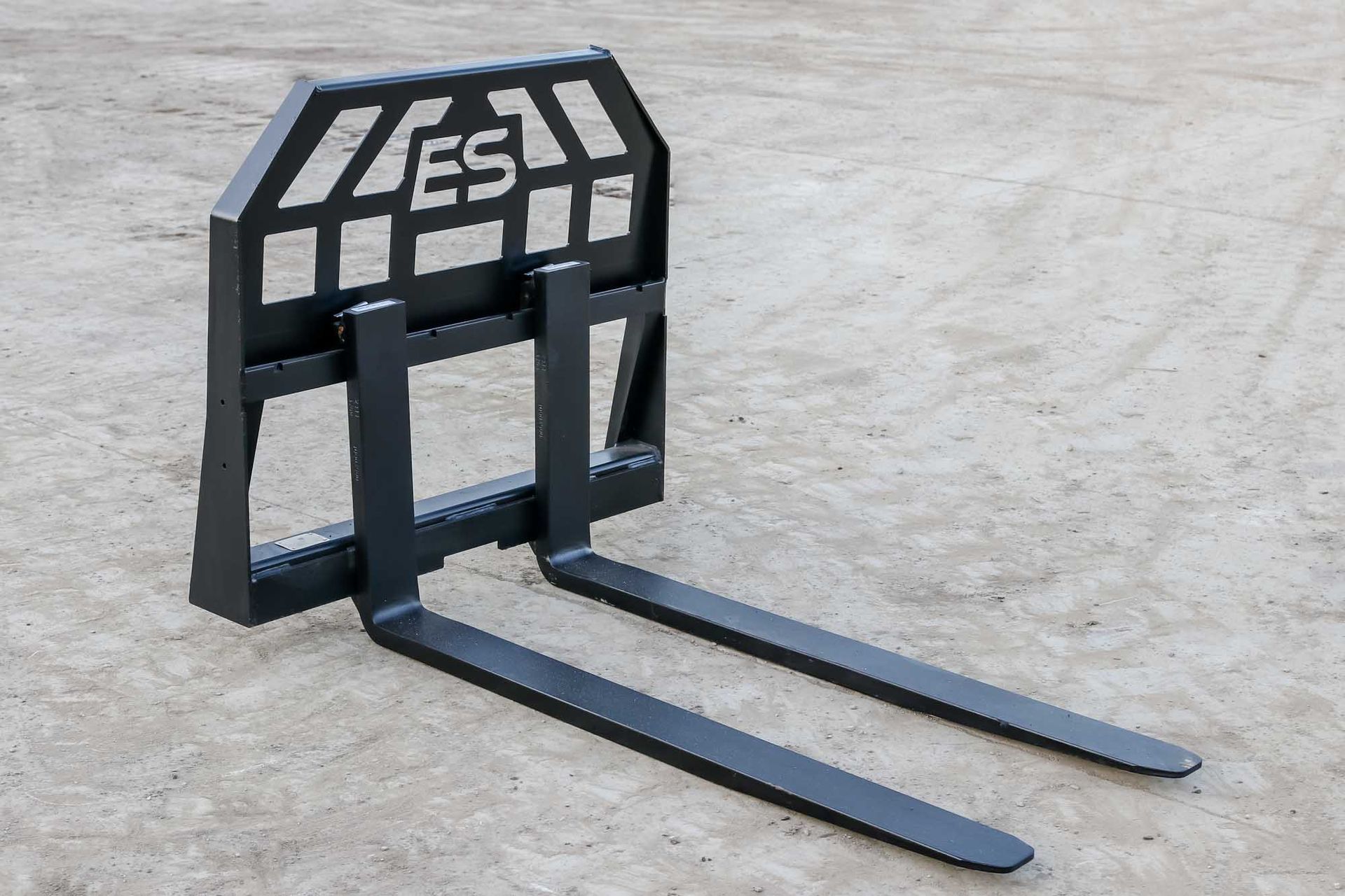 A pair of forklift forks sitting on a concrete surface