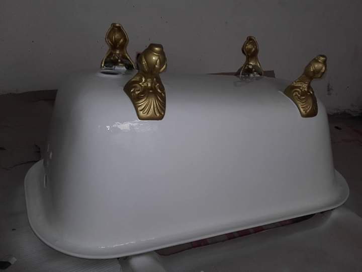 Bañera blanca con pies dorados ornamentados.