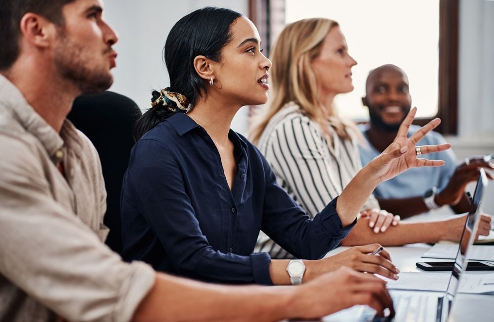 A group of people are sitting at a table having a meeting.