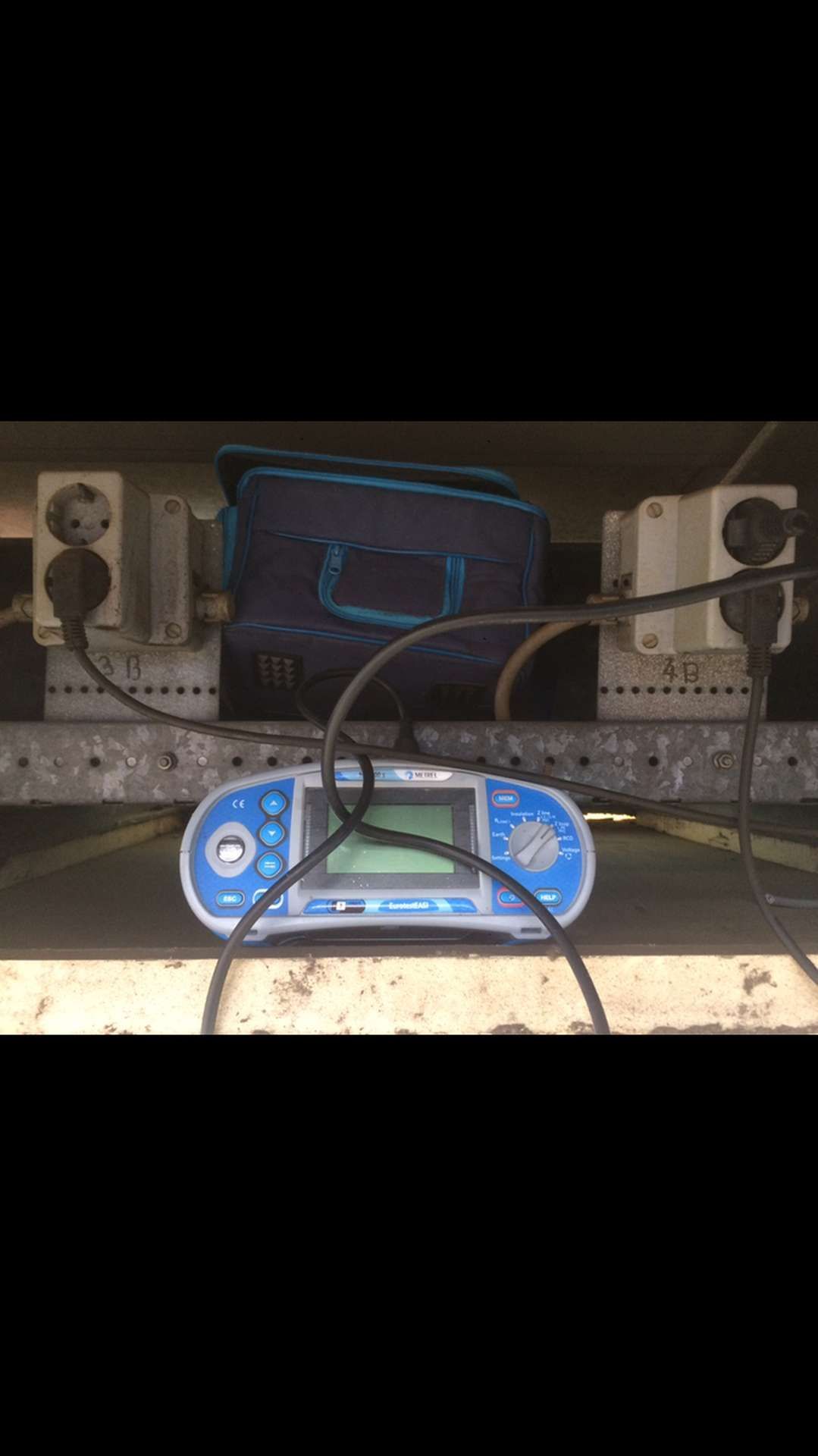 Een blauw-wit apparaat zit bovenop een stekkerdoos.