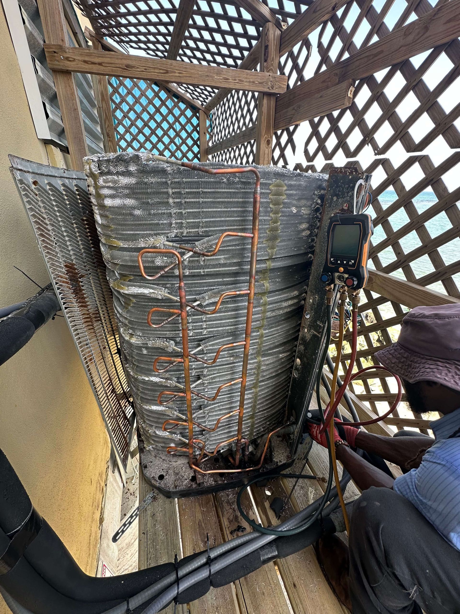 A man is working on an air conditioner outside of a building.