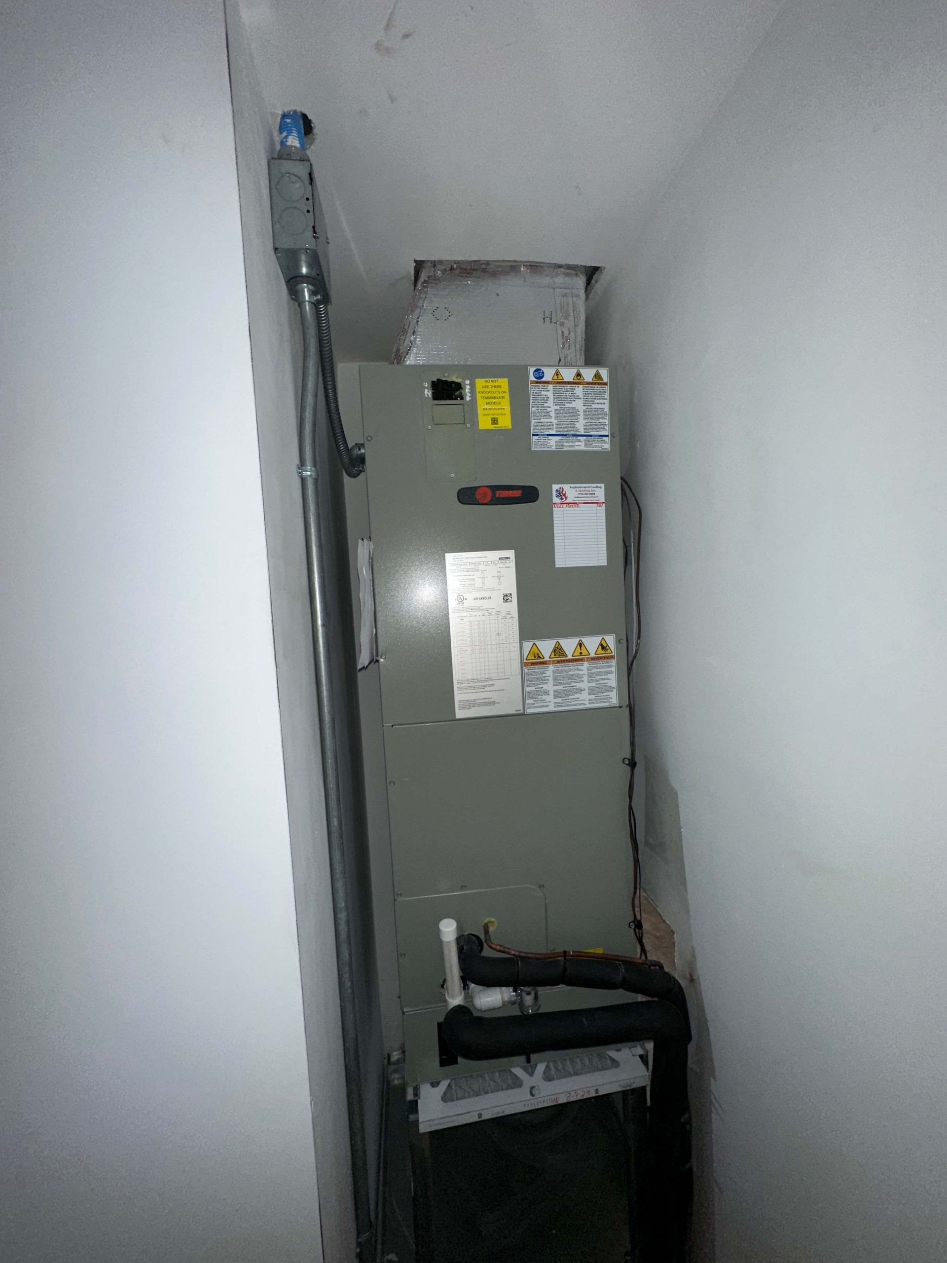 A large air conditioner is sitting in a corner of a room.