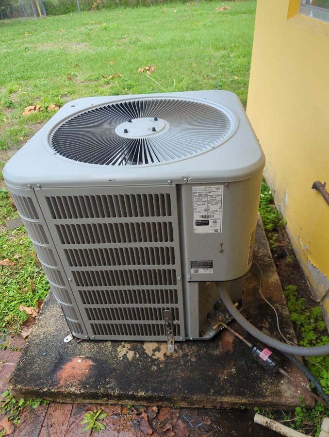 A large air conditioner is sitting on the side of a house.