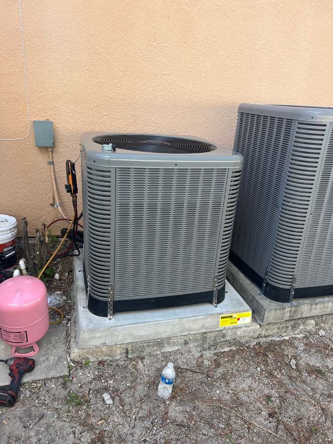 Two air conditioners are sitting next to each other on the side of a building.