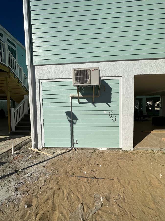 A house with a garage door and an air conditioner on the side of it.