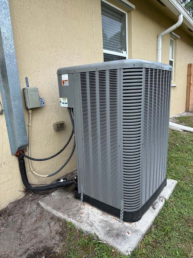 An air conditioner is sitting on the side of a house.