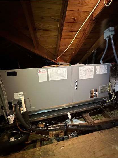 An air conditioner is sitting in the attic of a house.