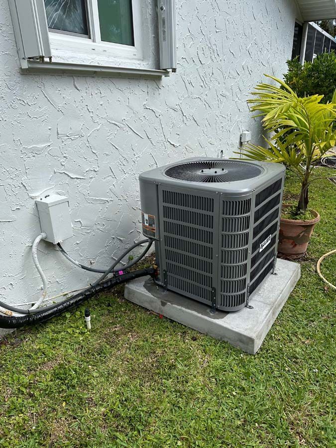 An air conditioner is sitting on the side of a house next to a window.
