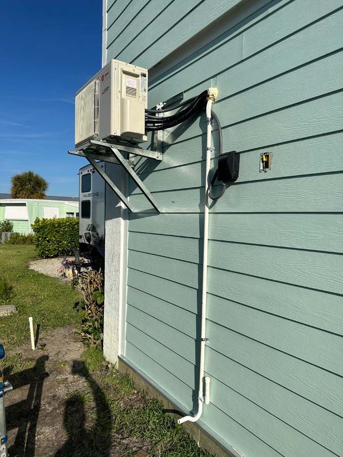 A white air conditioner is mounted on the side of a house.