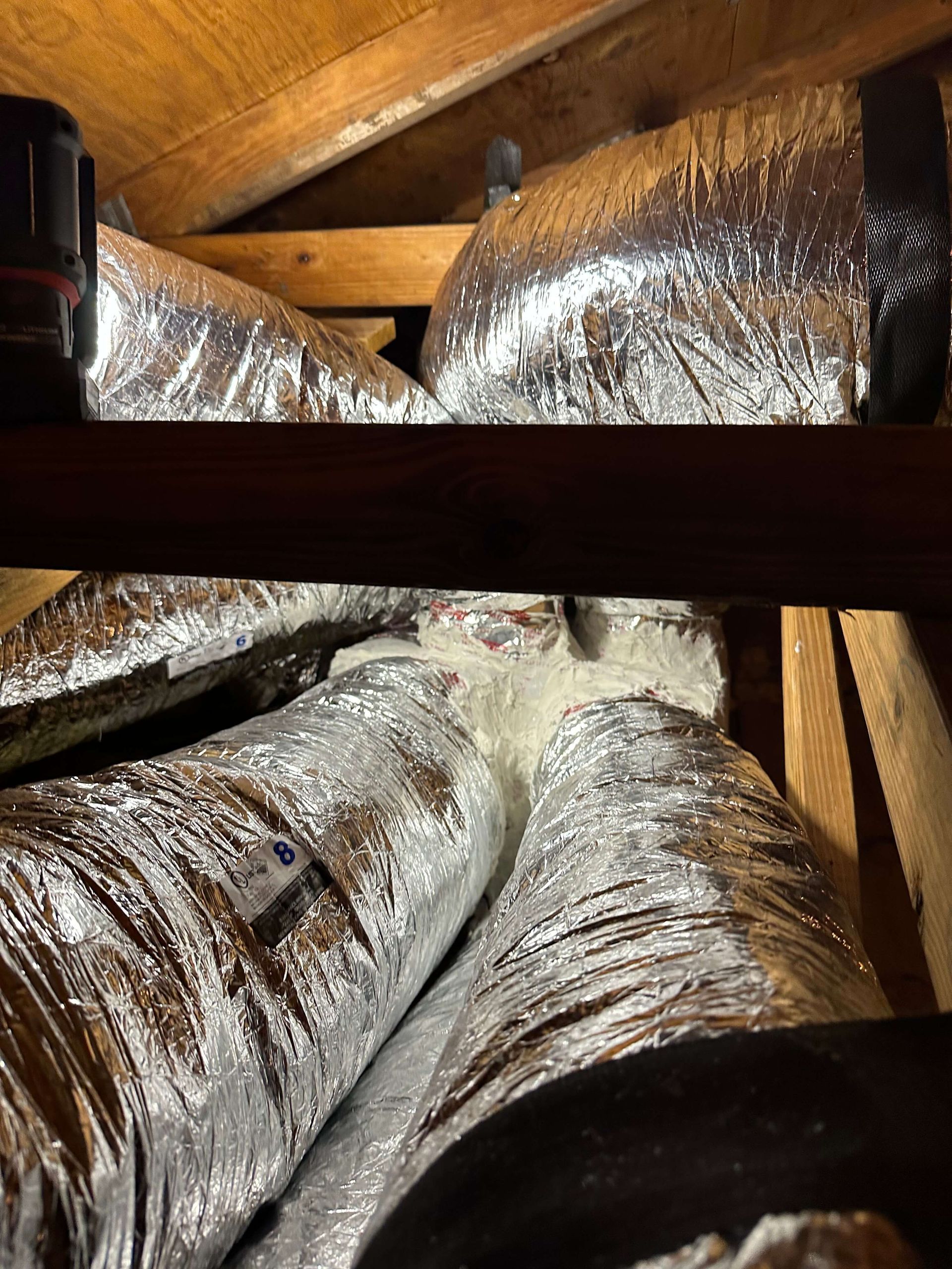 A bunch of ducts are sitting on top of each other in an attic.