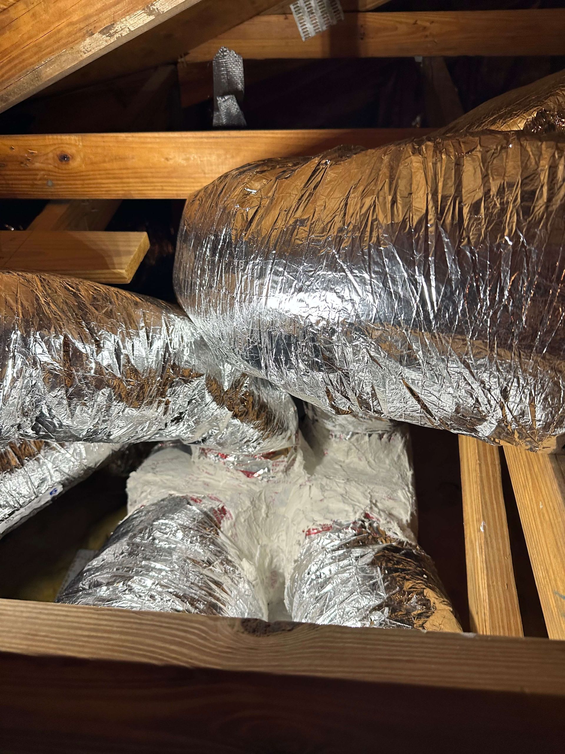 A bunch of ducts are wrapped in aluminum foil in a wooden box.