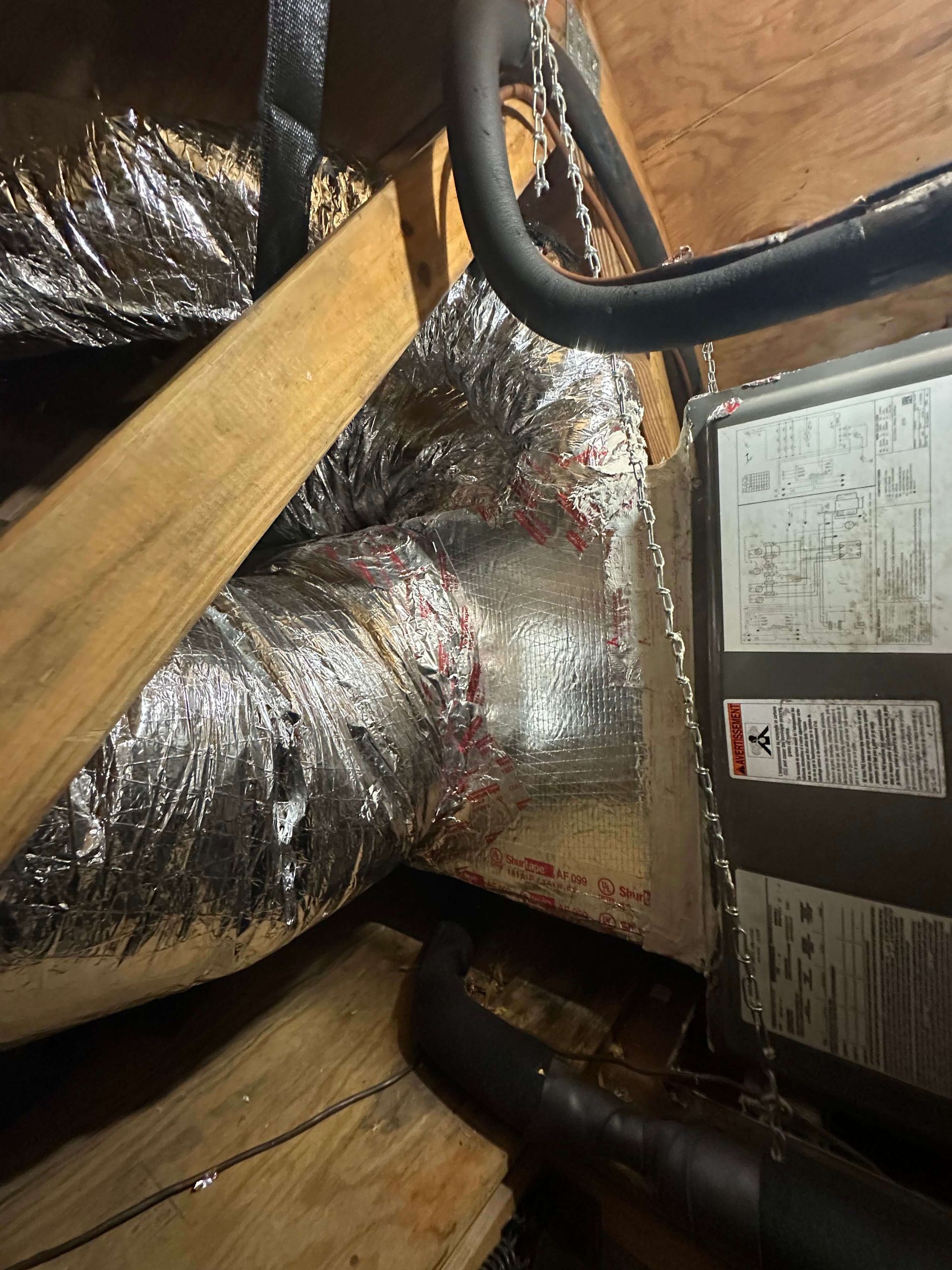 A duct with aluminum foil on it is sitting on top of a wooden floor.