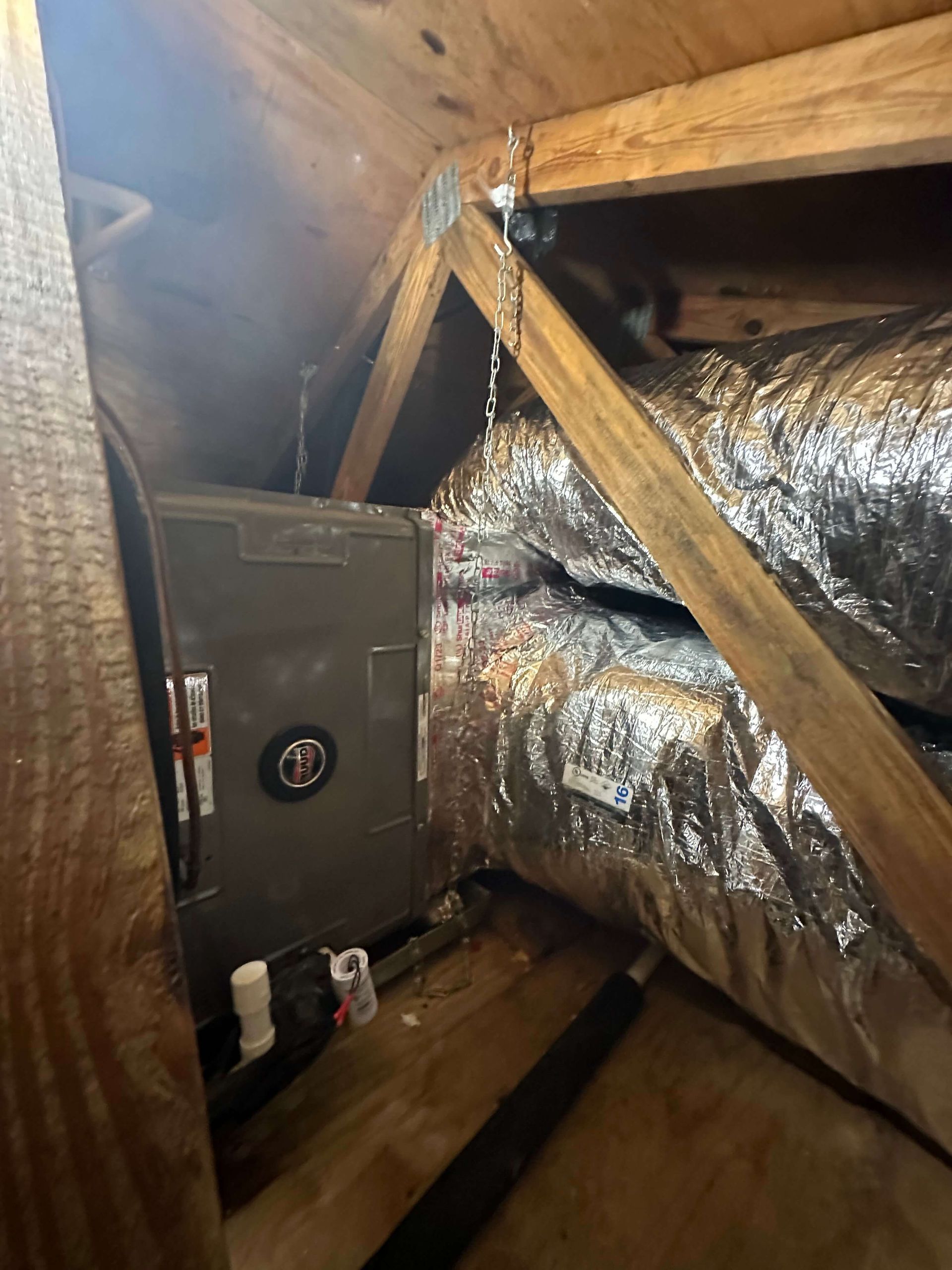 An air conditioner is sitting in the attic of a house.