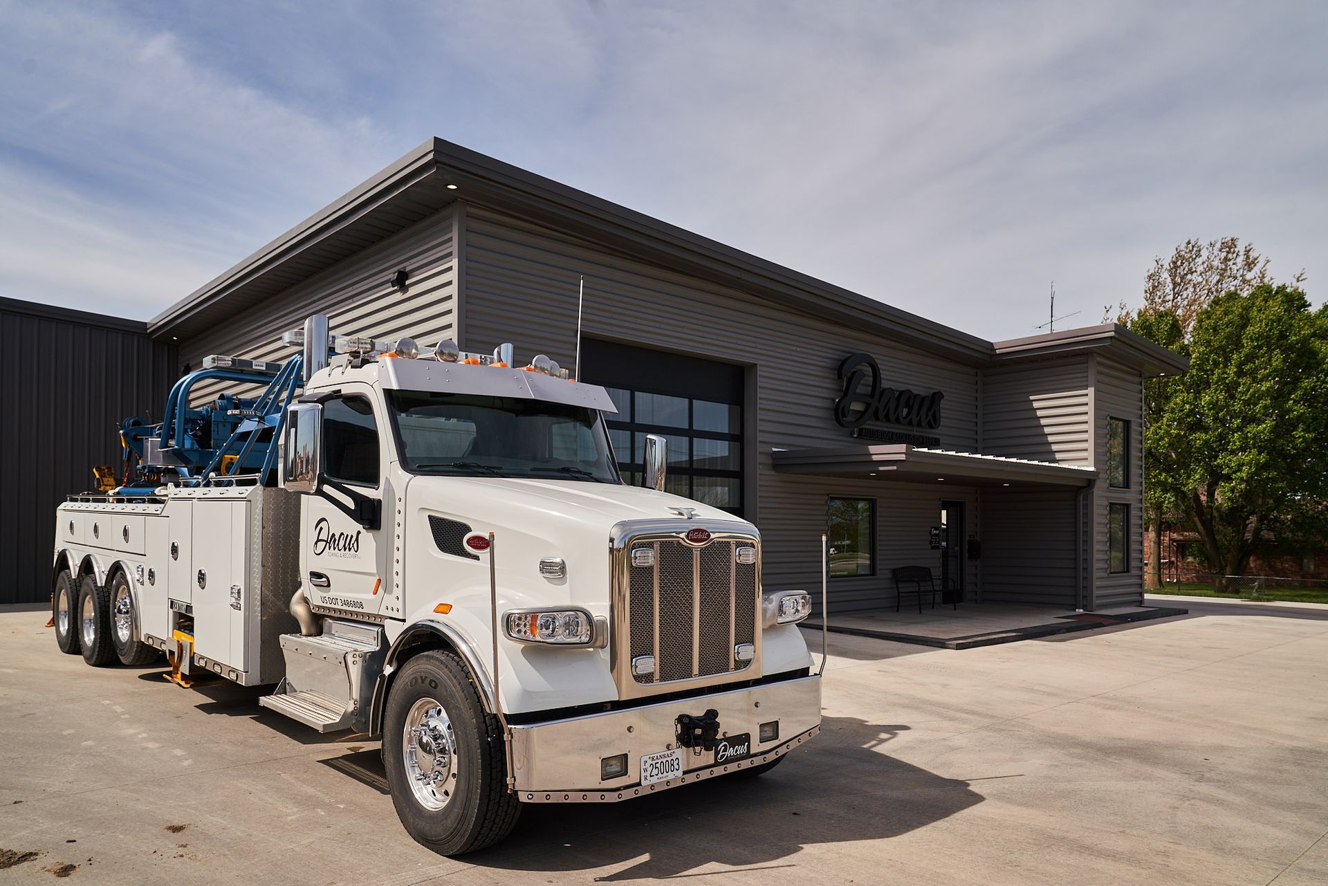 White tow truck parked in front of a modern gray building.