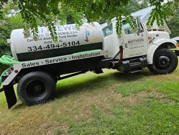 White utility truck parked on grass, labeled 
