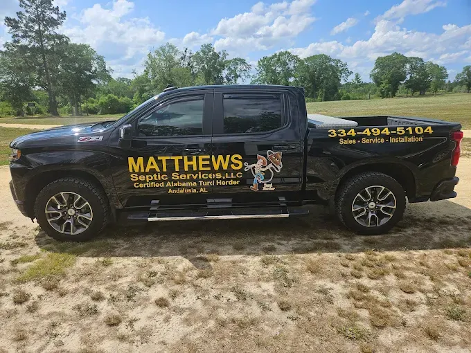 A black pickup truck parked on dirt with yellow text reading 