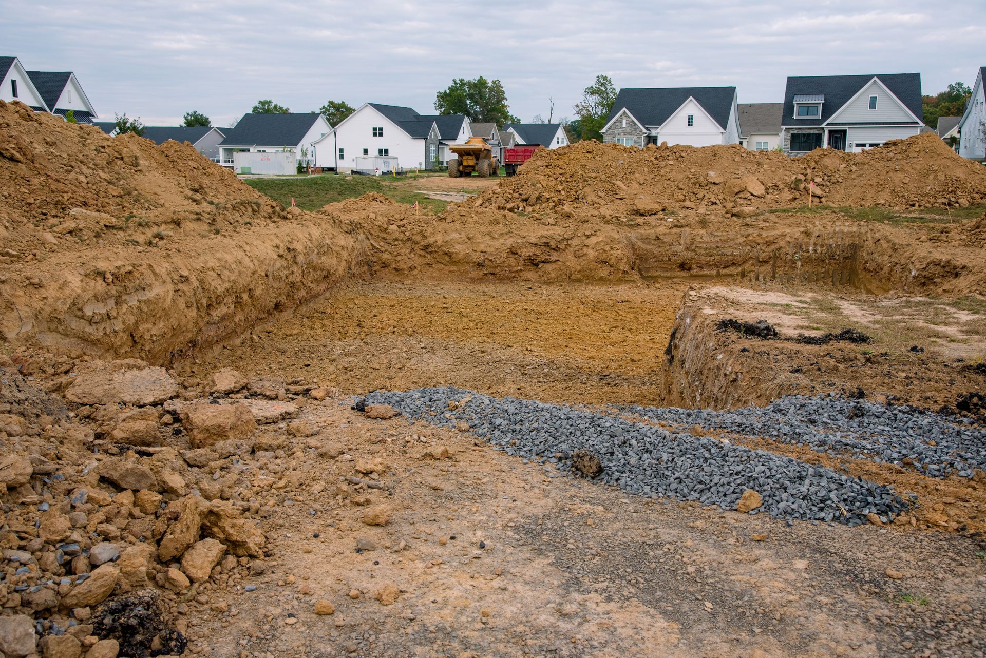 A leach field for a septic system with rows of black plastic drain covers resting on sand, connected to a central junction.