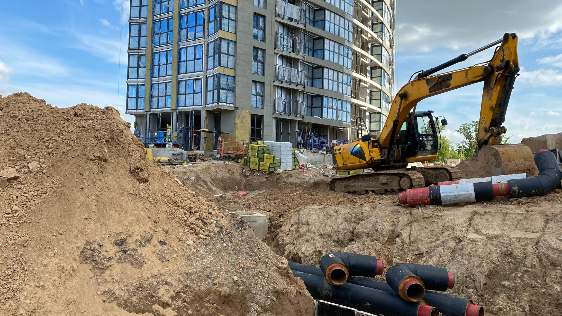 A construction site with a large pile of dirt and a building in the background.