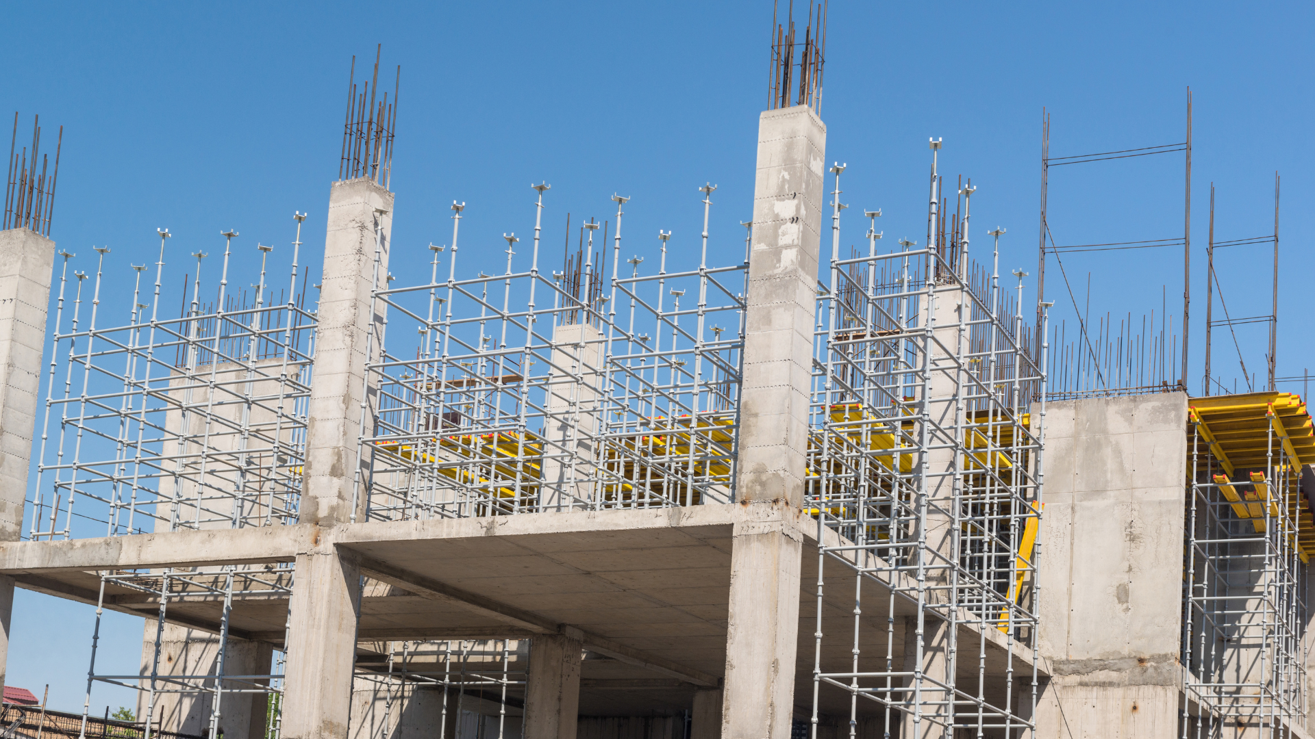 A large building under construction with scaffolding around the pillars.