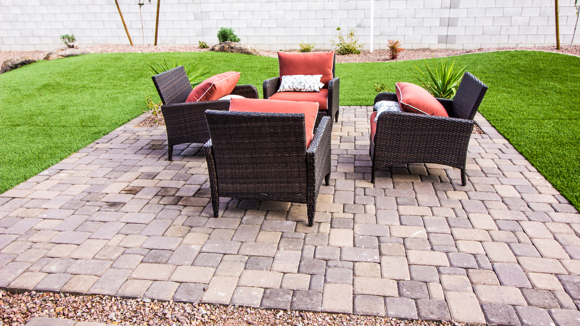A patio with chairs and a couch on it in a backyard.