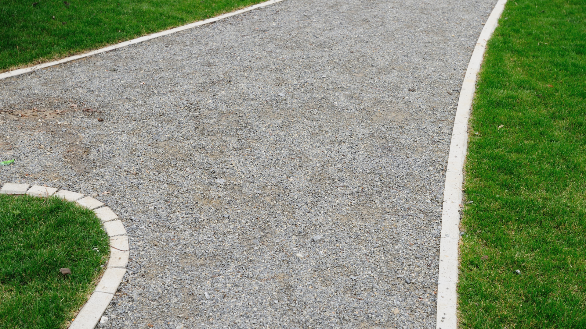 A gravel path going through a lush green field.