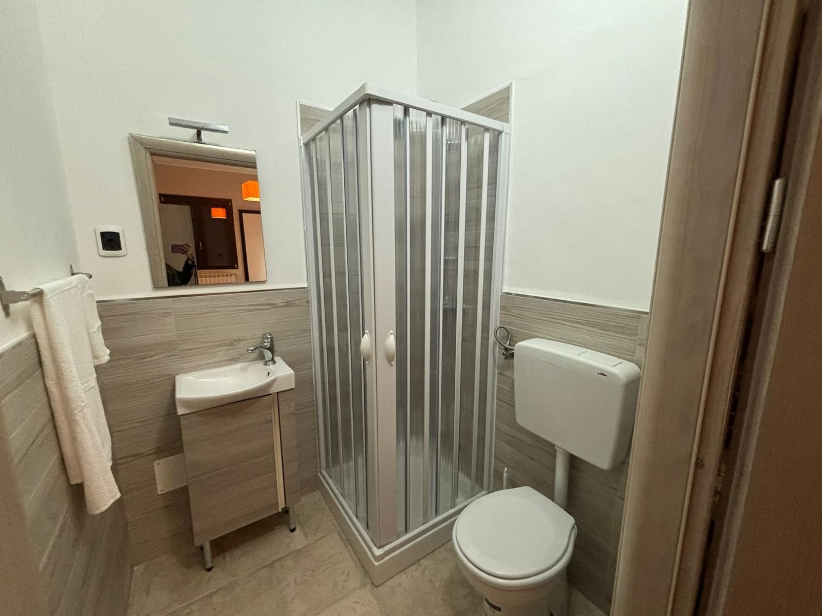 Un bagno con wc, lavandino, doccia e specchio.