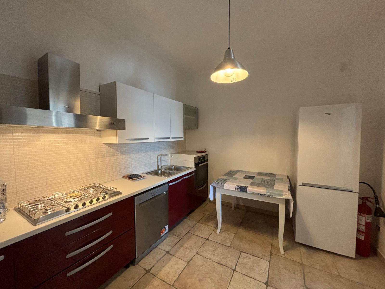 Una cucina con fornello, frigorifero, lavastoviglie e tavolo.