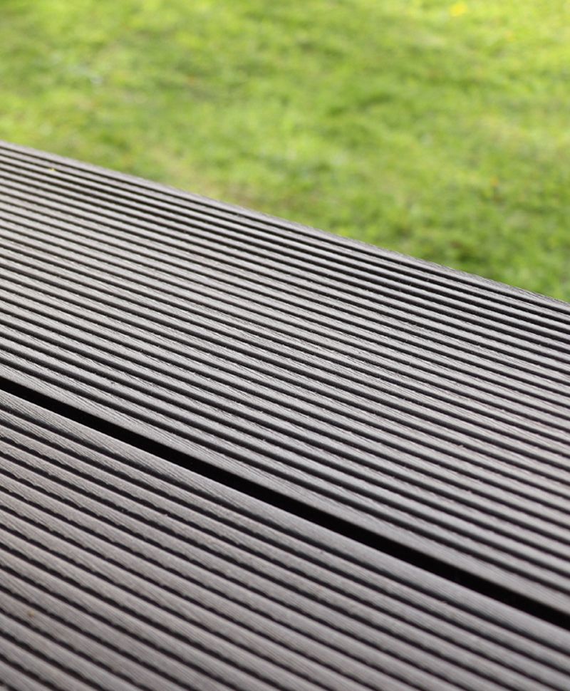 Close-up of grooved, dark wood planks with a green grassy background