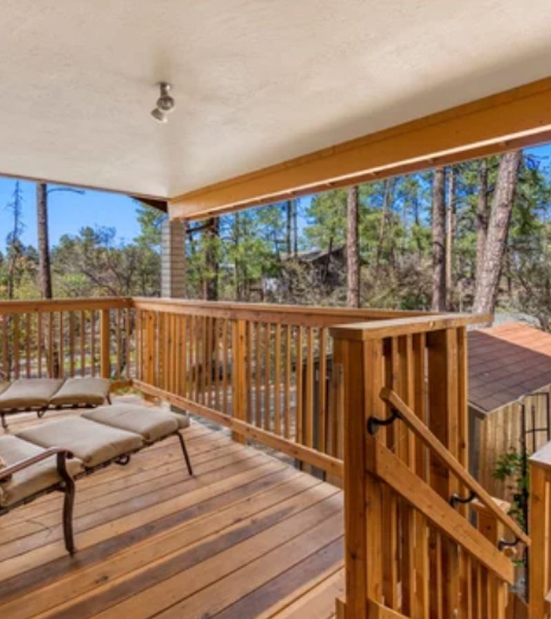 Wooden deck overlooking a forest with a sun lounger