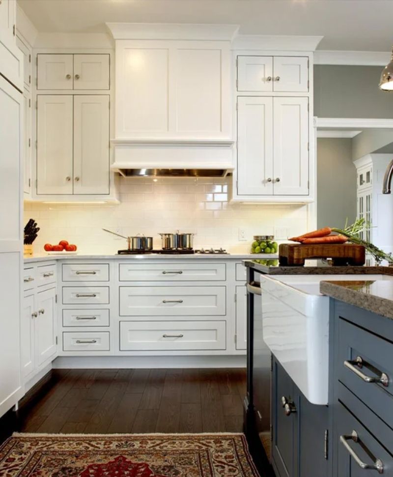 White kitchen with dark wood floors, stainless steel appliances, and a gray island