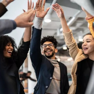 Een groep diverse mensen met opgestoken handen, lachend op kantoor, vieren succes.