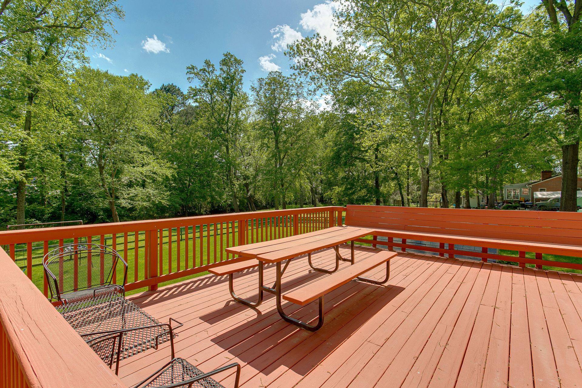 A large wooden deck with a picnic table and benches.