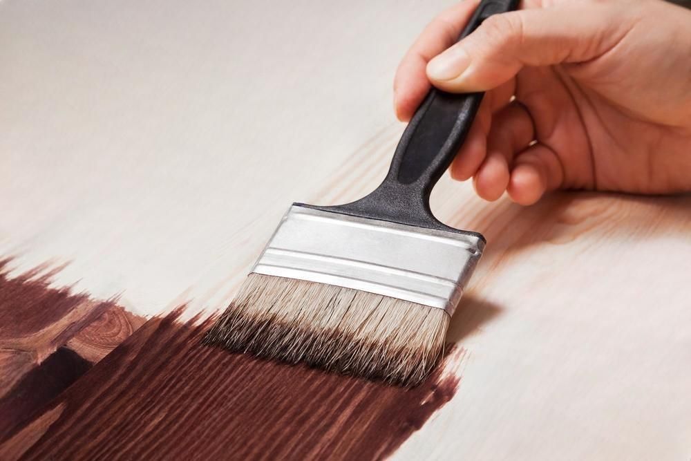 A person is painting a piece of wood with a brush.