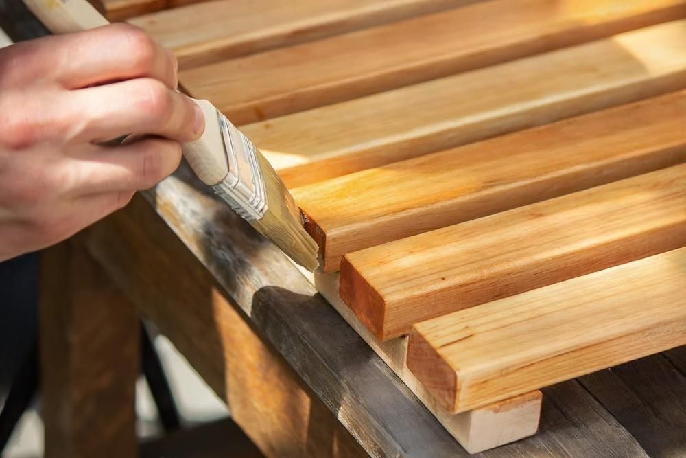 A person is painting a piece of wood with a brush.