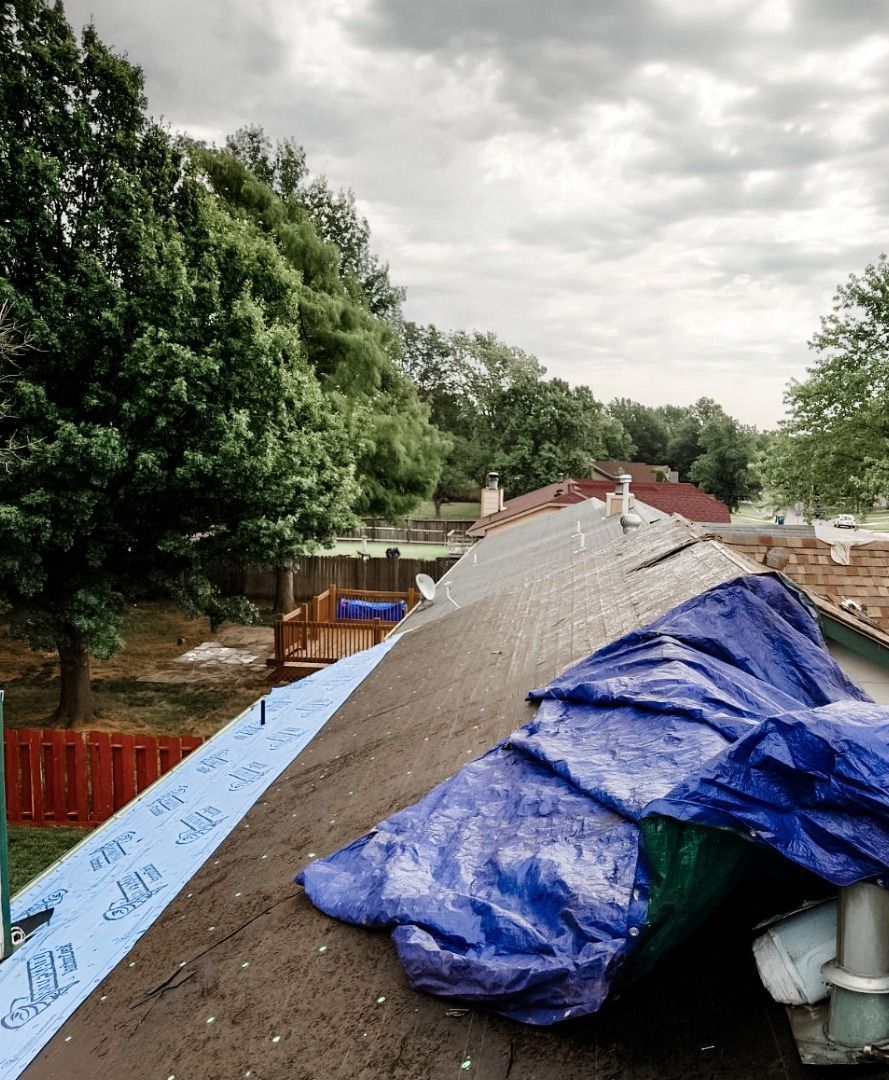 A blue tarp is covering the roof of a house.