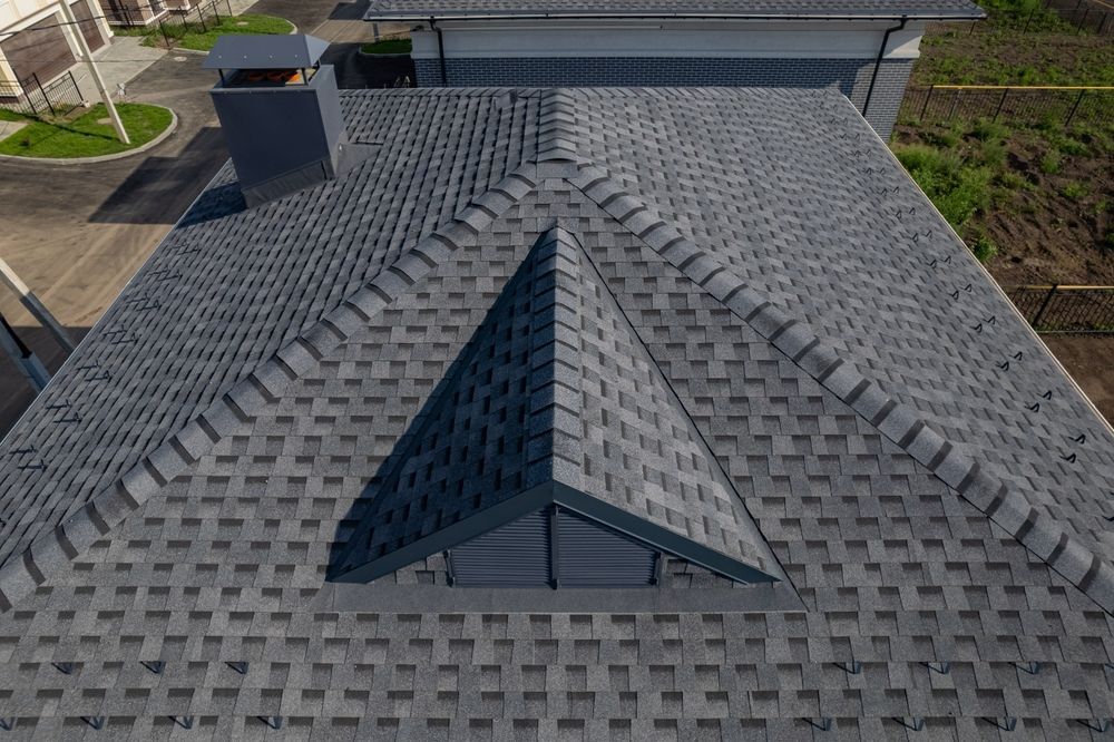 An aerial view of a house with a gray roof and a chimney.